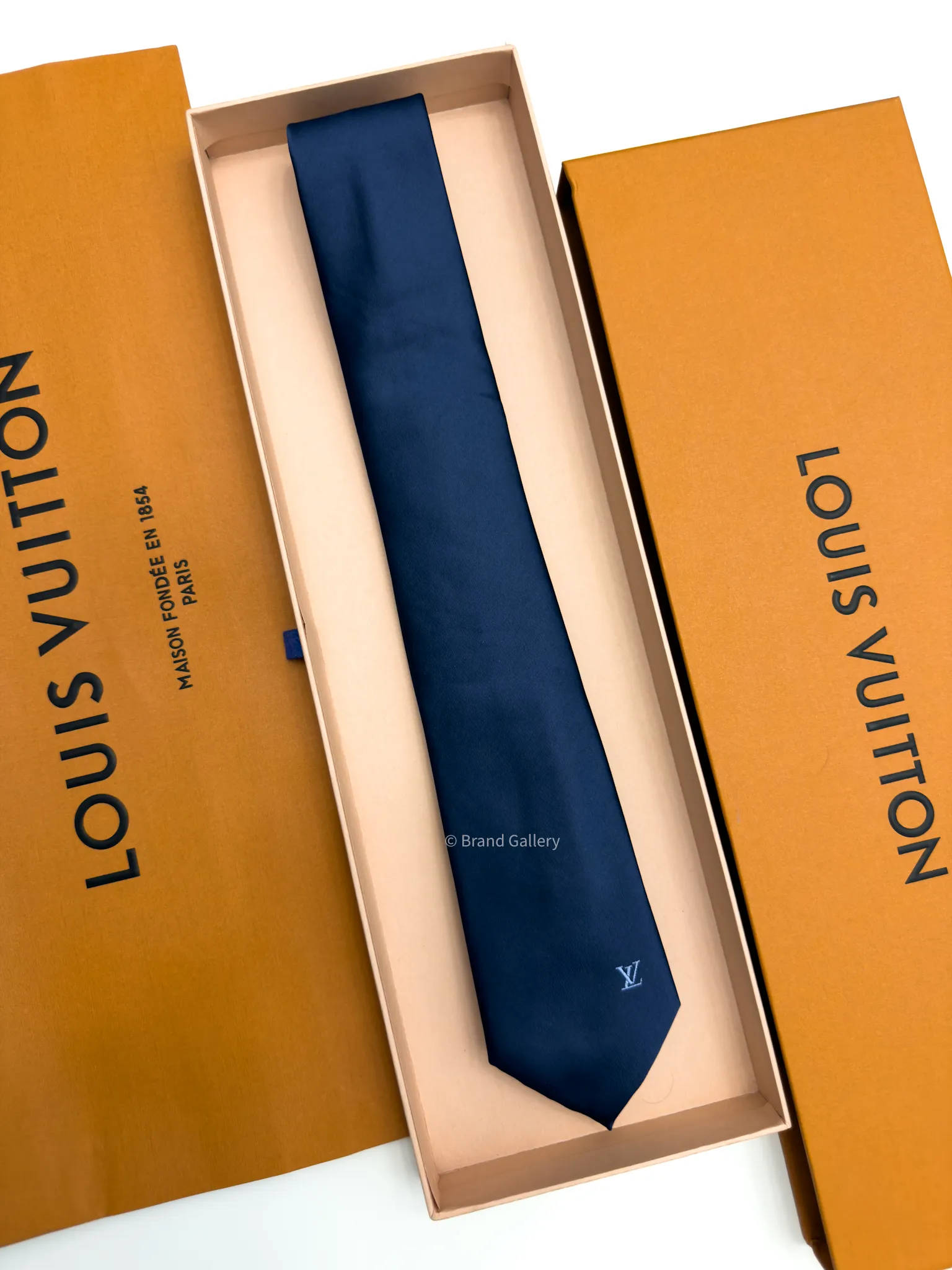 Navy blue solid silk tie with subtle light blue motif near the tip