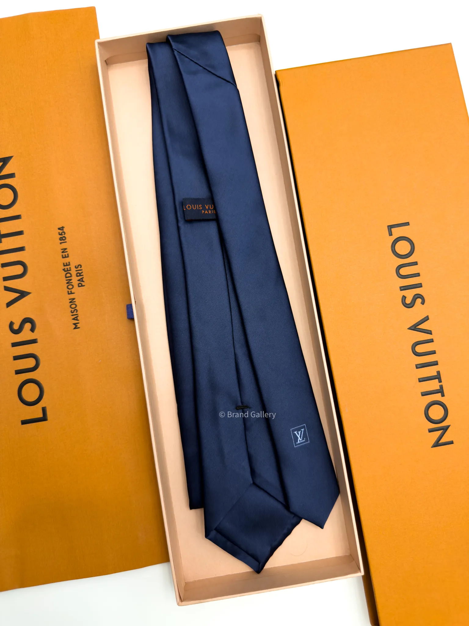 Navy blue solid silk tie with subtle light blue motif near the tip