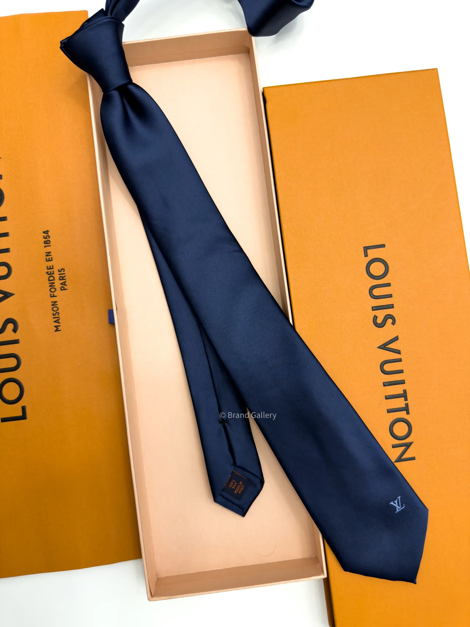 Navy blue solid silk tie with subtle light blue motif near the tip