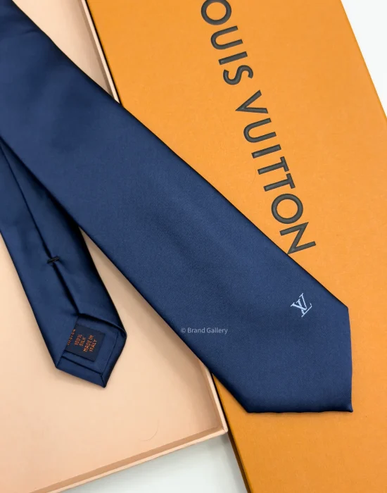 Navy blue solid silk tie with subtle light blue motif near the tip